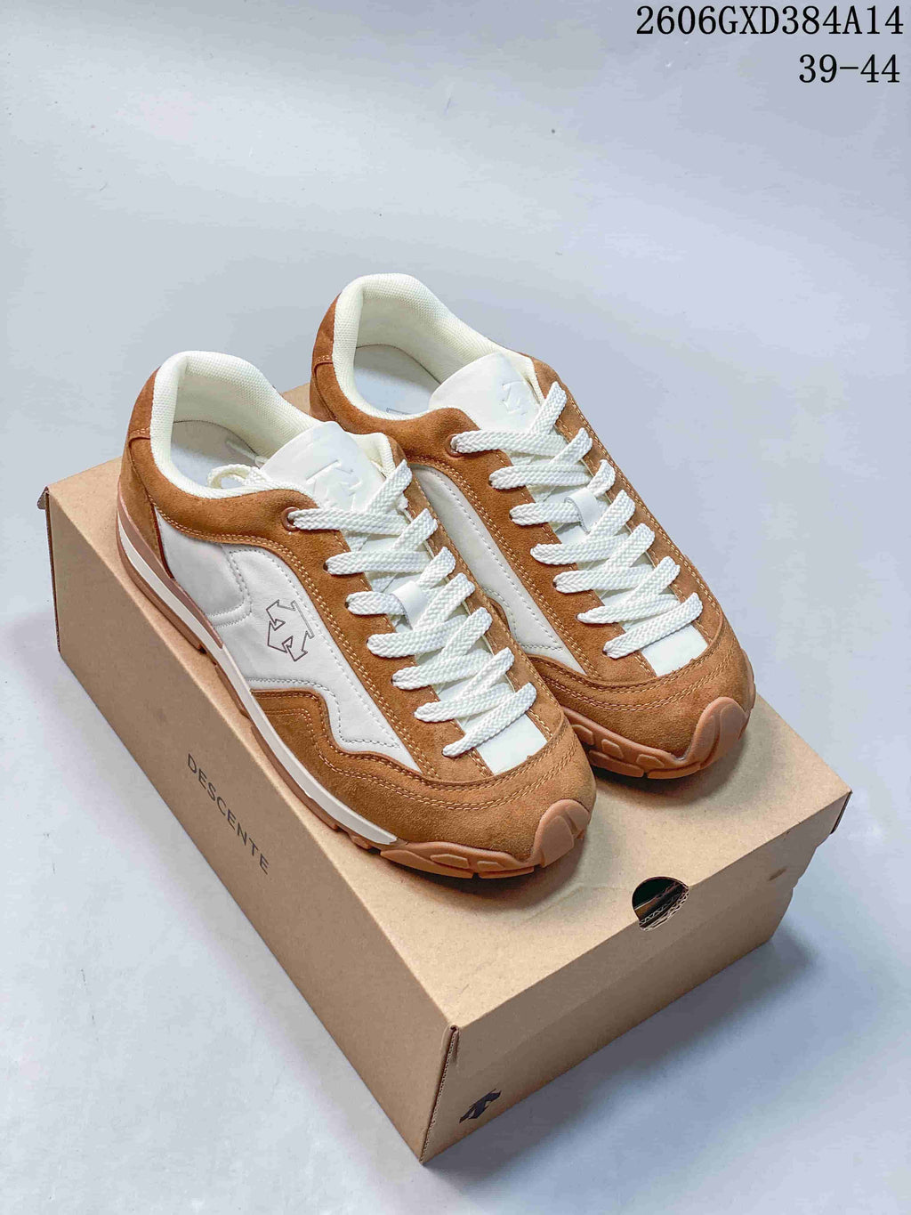 Brown and white Descente low-top sneakers shown on a shoe box