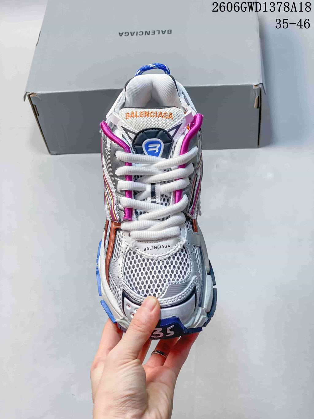 Front view of a silver and white Balenciaga Runner sneaker with white laces and colorful accents