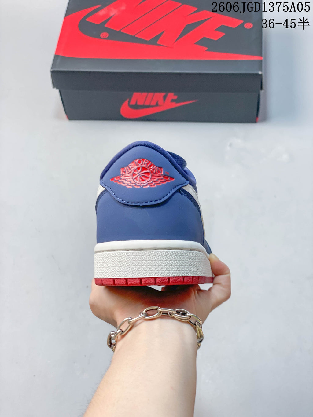 Heel view of the blue Jordan 1 Low sneaker with a red embroidered emblem