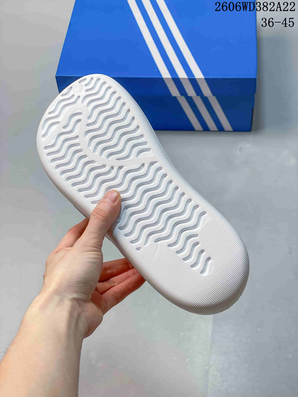 Textured outsole of a white slide with a wavy tread pattern
