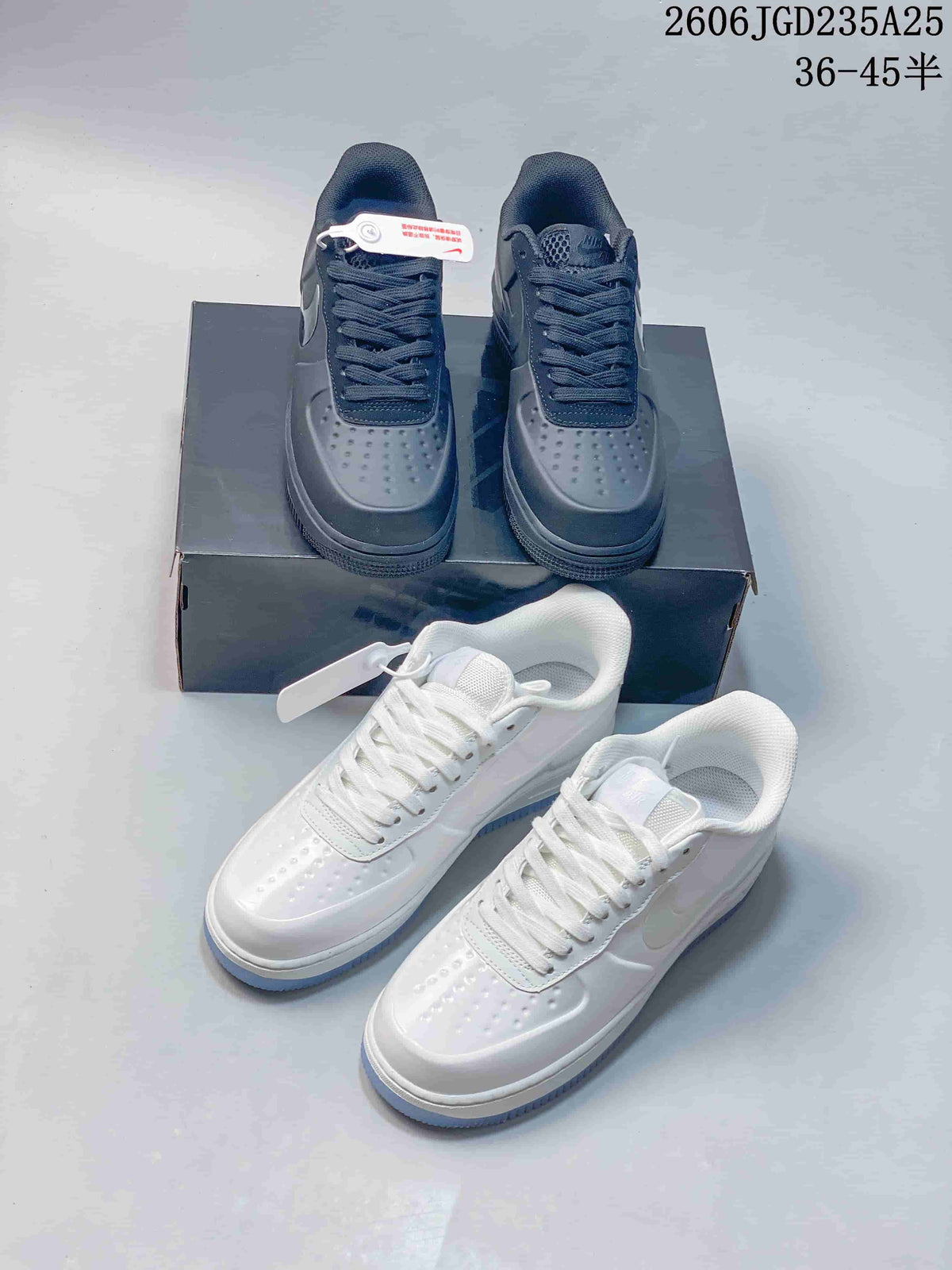 White and charcoal low-top sneakers displayed together on and in front of a dark shoe box