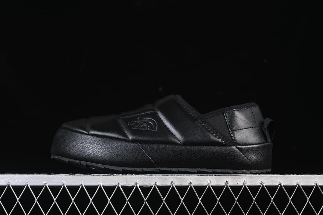 Side profile of a black quilted The North Face mule.