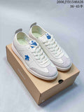 White and light gray Descente low-top lace-up sneakers displayed on a shoe box.