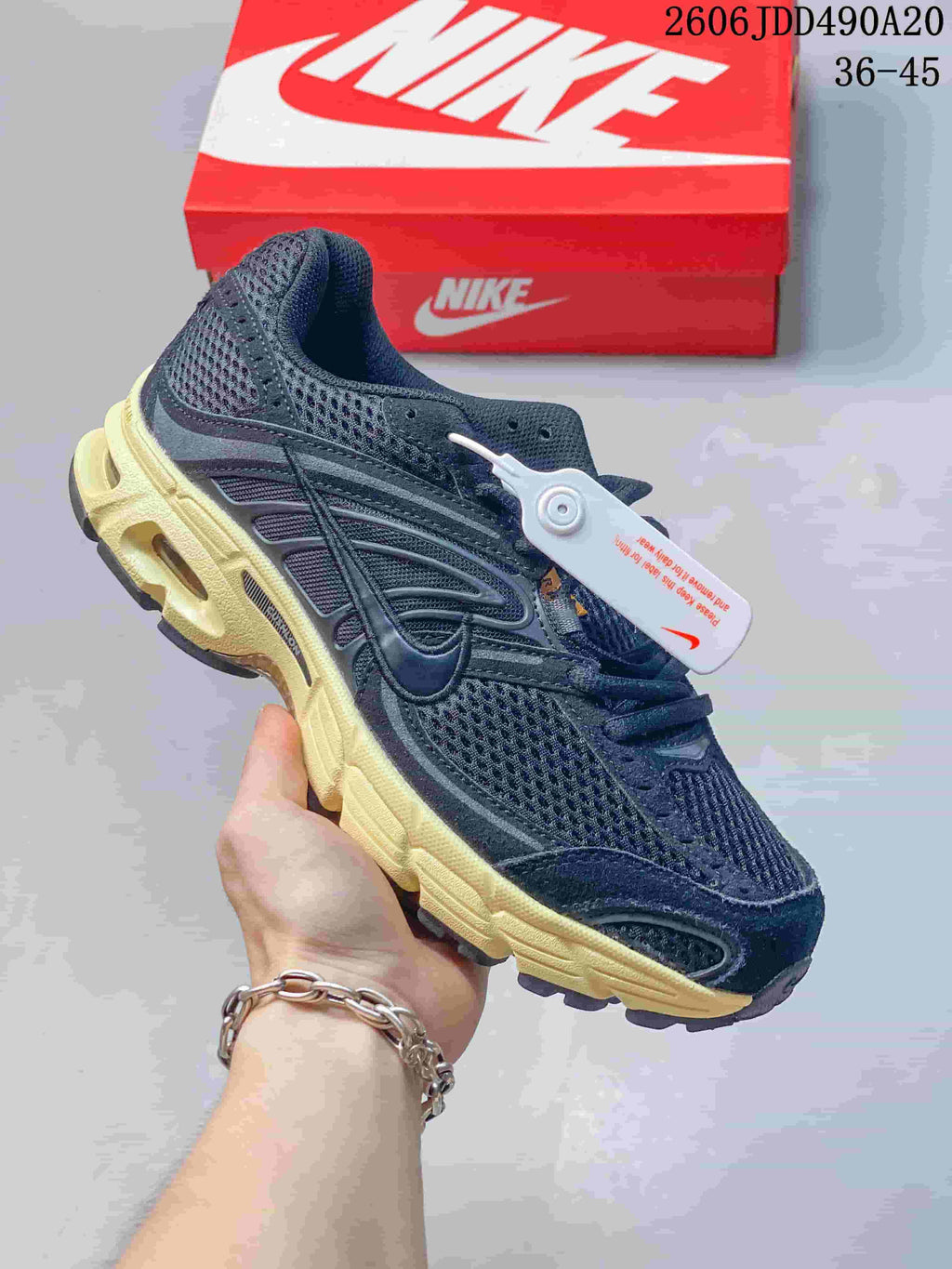 Dark Nike Air Max Moto 2K sneaker with a pale yellow sole and mesh upper