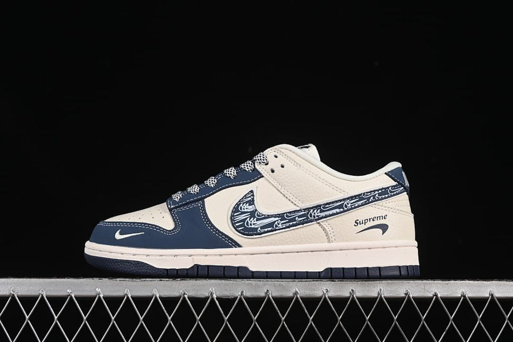 Side view of a cream and navy low-top sneaker with a patterned Swoosh and contrast stitching.