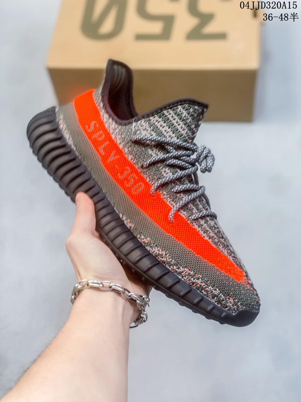 Side view of a gray patterned sneaker with a bright orange stripe and dark ribbed sole.