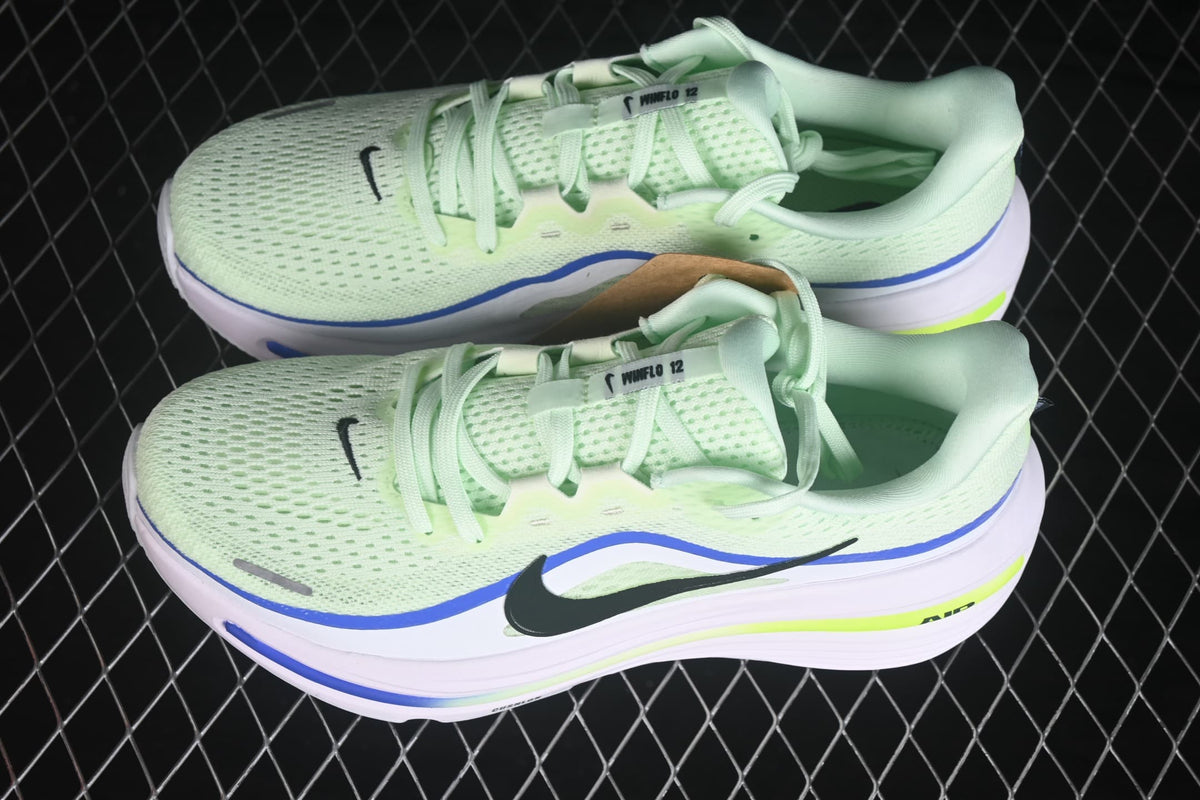 Top view of the pair showing perforated pale green uppers, laces, blue edging and black Swoosh details.