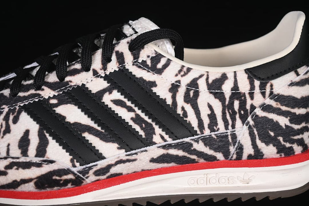 Close-up of the black side stripes, animal-print upper, laces, and red midsole detail.
