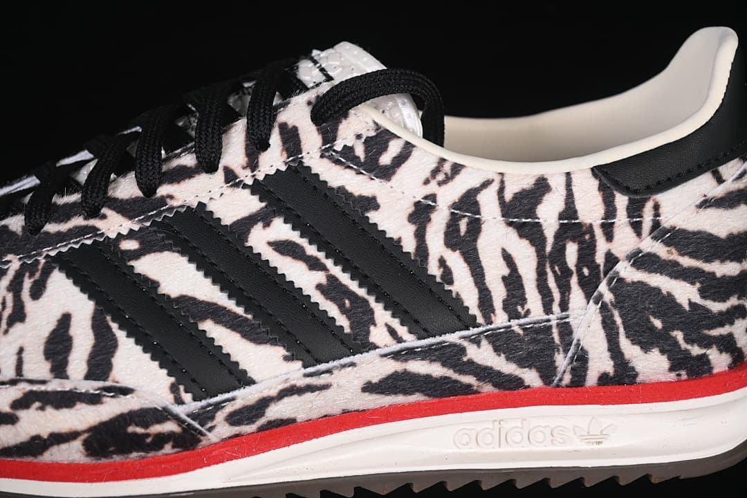 Close-up of the black side stripes, animal-print upper, laces, and red midsole detail.
