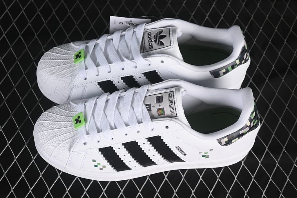 Pair of white adidas Superstar II J sneakers with black stripes and Minecraft-inspired details