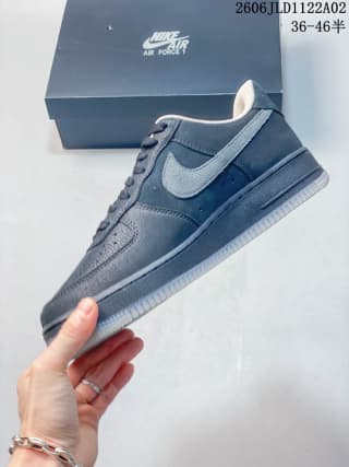 Side view of a black Nike Air Force 1 low-top sneaker held above its branded box.