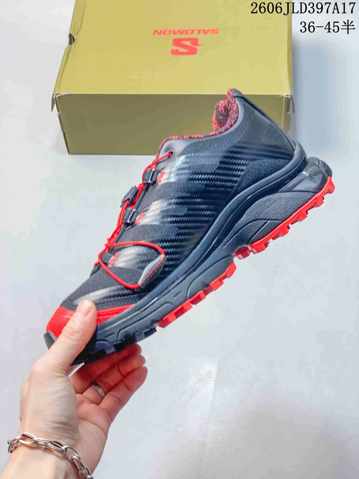 Side view of the shoe showing the dark upper, red accents and rugged outsole