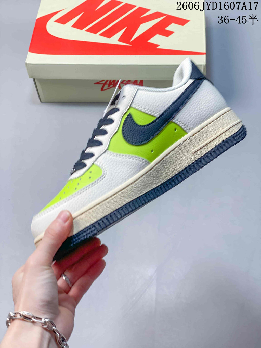 Side view of the sneaker with bright lime panels, navy Swoosh and white upper.