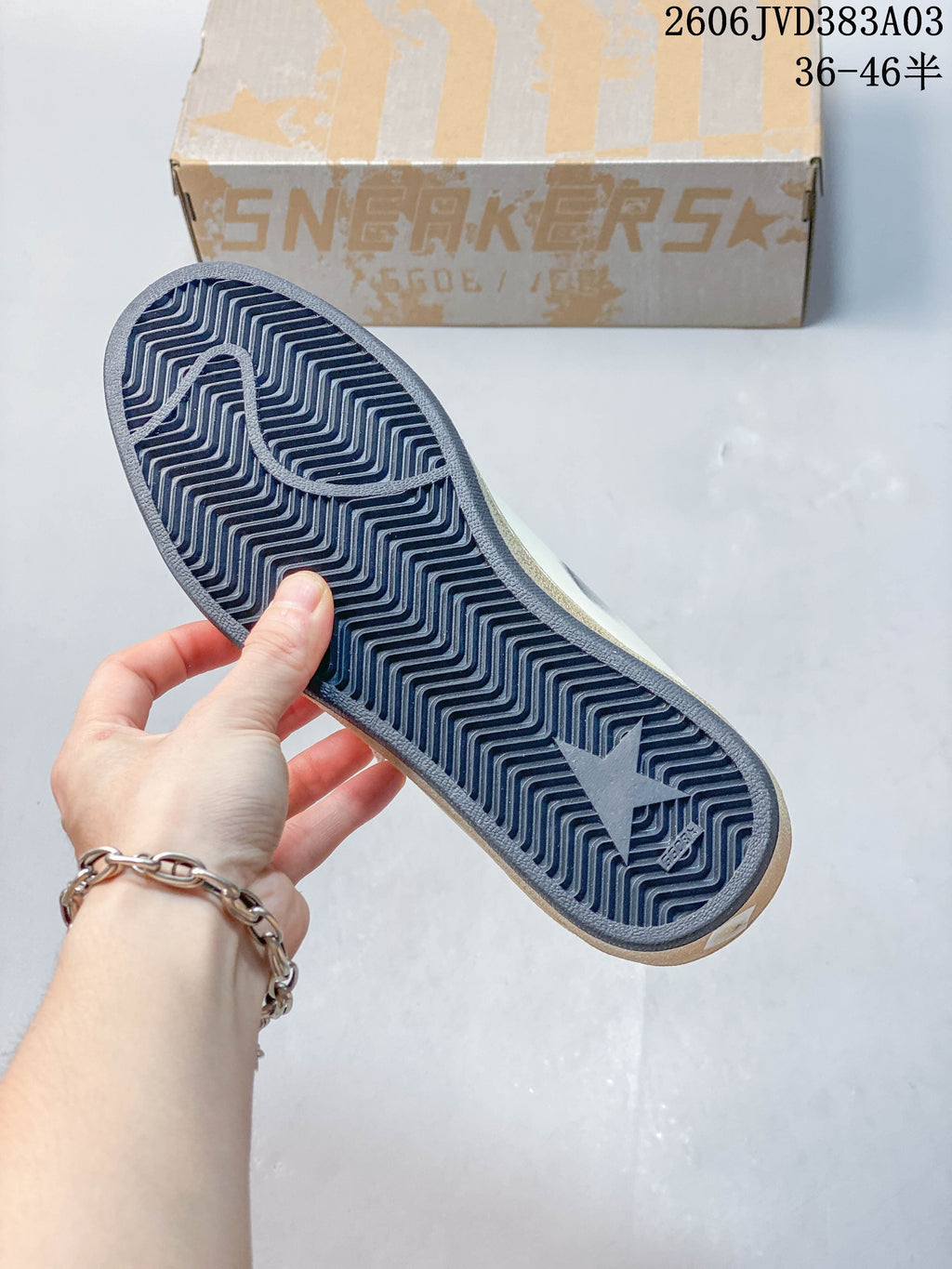 Underside of sneaker showing a dark outsole with a zigzag tread pattern