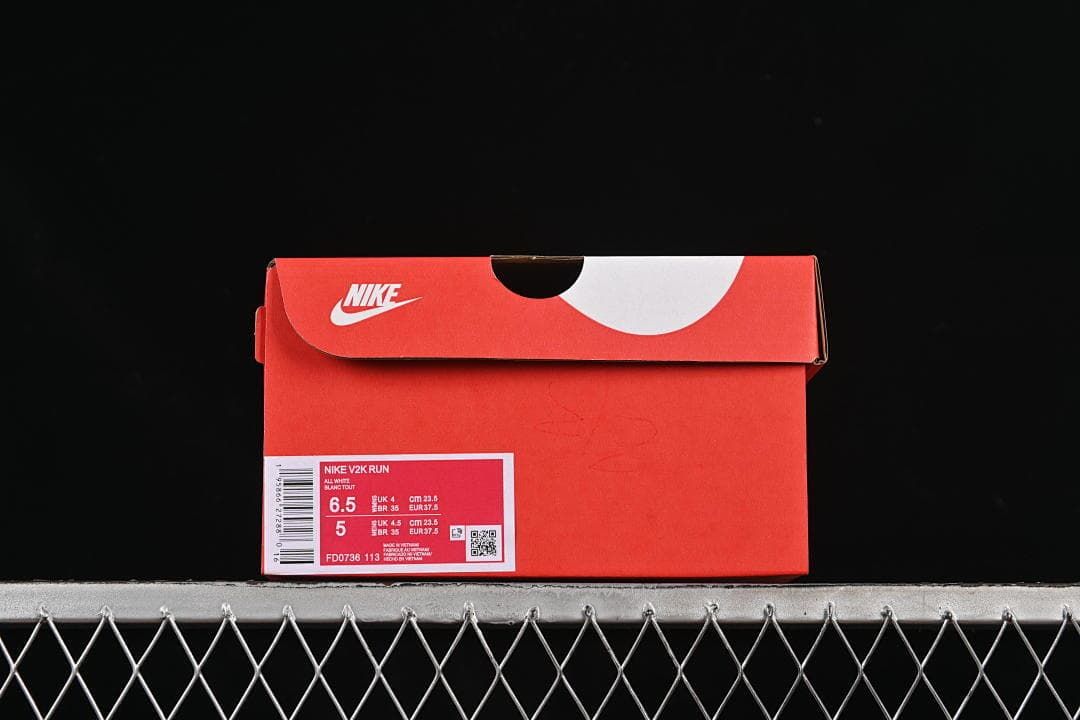 Shoe box label identifying Nike V2K Run, style FD0736-113, and a photographed EU 37.5 size.