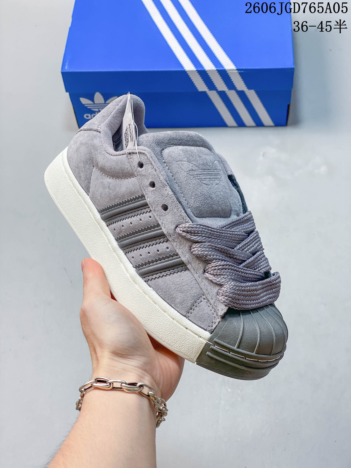 Close side view of a grey Adidas Originals Superstar XLG sneaker with a shell toe and chunky light-colored sole.