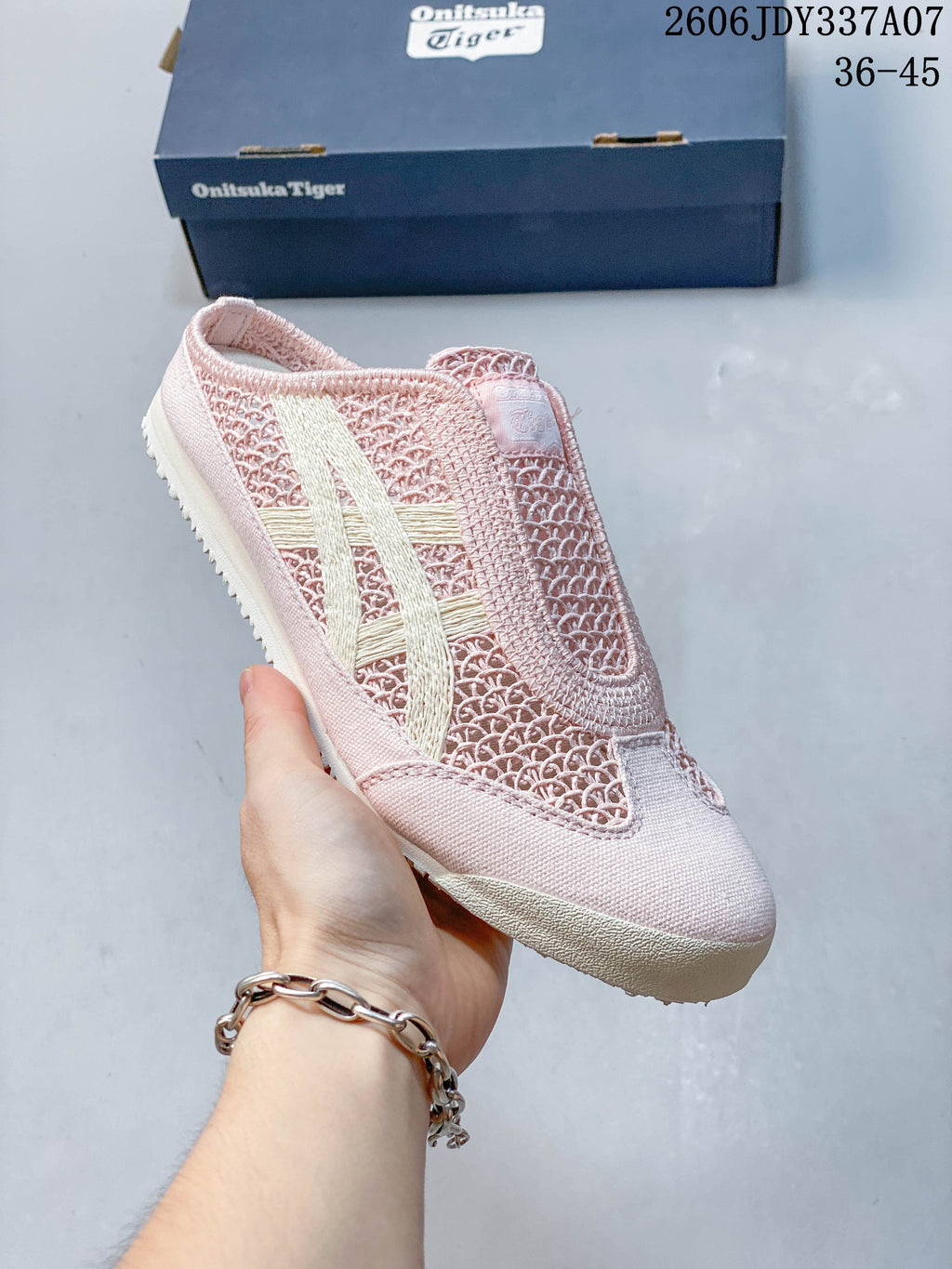 Angled side view of the pink shoe with cream stripes and textured outsole