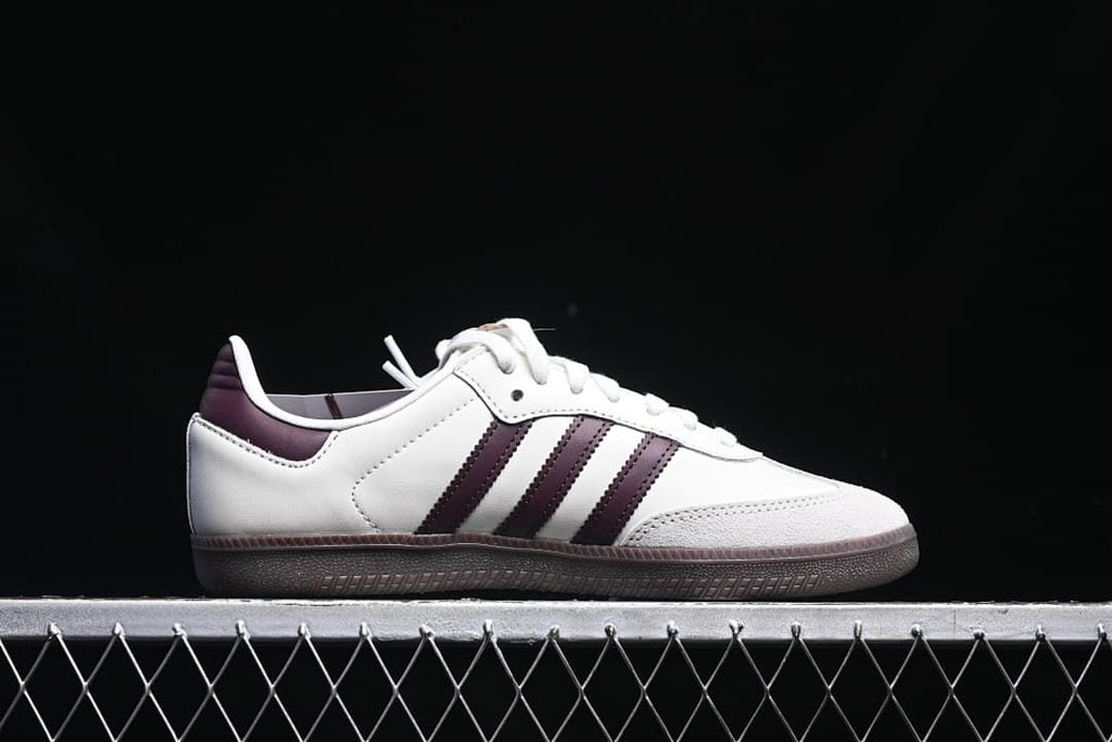 Side profile of the white sneaker with burgundy stripes and dark outsole