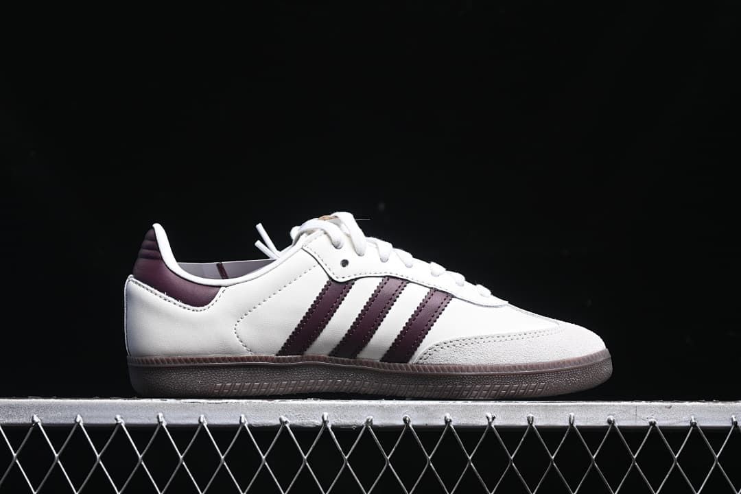 Side profile of the white sneaker with burgundy stripes and dark outsole