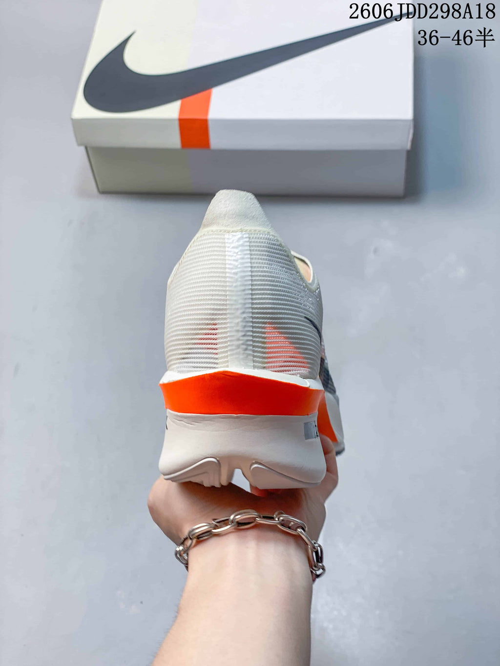 Rear view of a cream Nike Vaporfly shoe with an orange heel accent