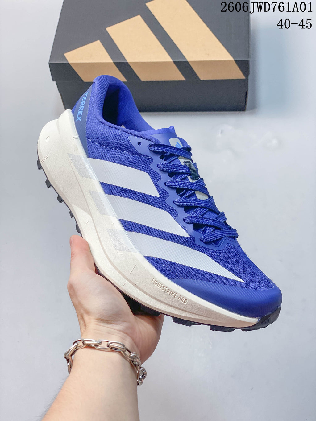 Blue Adidas Terrex trail running shoe with white stripes and a light-colored midsole