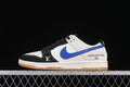 Side view of a white, black, and blue low-top sneaker with a gum-colored outsole and visible swoosh and monogram-style graphics.