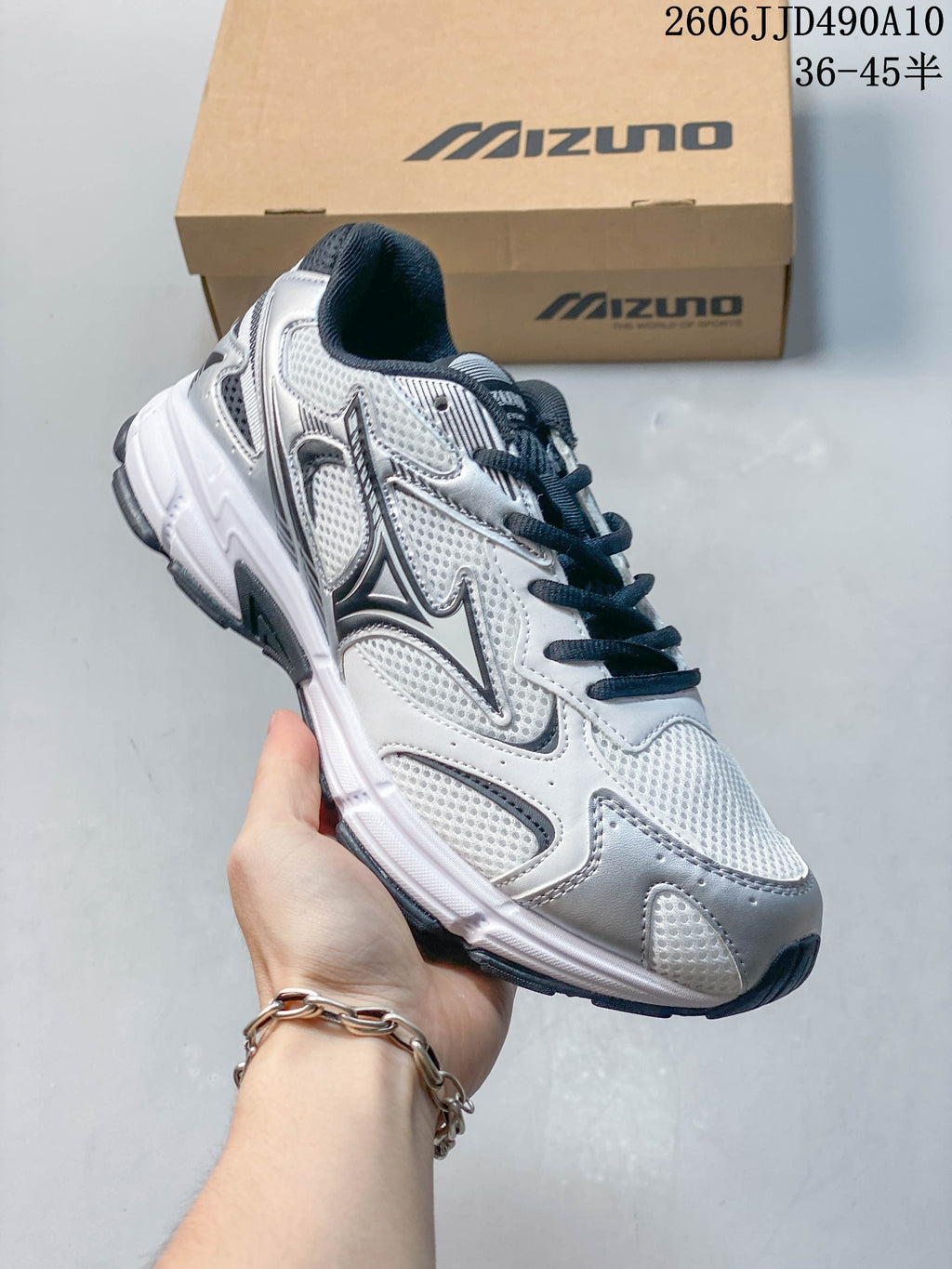 White and silver mesh Mizuno sneaker with dark laces and a white sole.