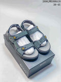 Pair of gray open-toe sandals with adjustable straps and yellow accents on a shoe box.