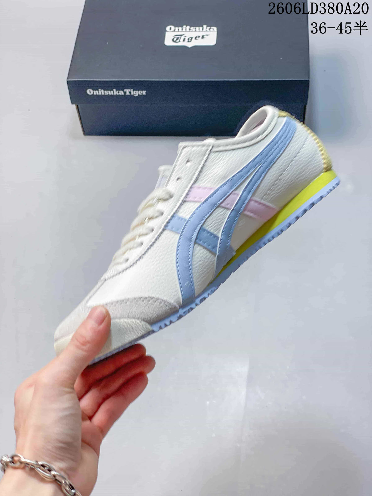 Side profile of a white-toned sneaker with light blue and pink stripes and a yellow heel accent.