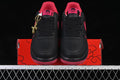 Pair of black low-top sneakers with red accents and red outsoles, shown from the front