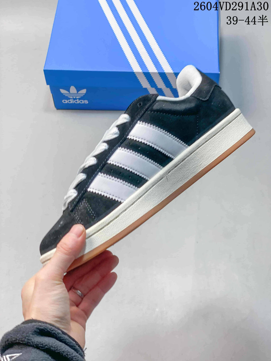 Side profile showing the dark upper, three contrasting stripes, off-white midsole and gum outsole