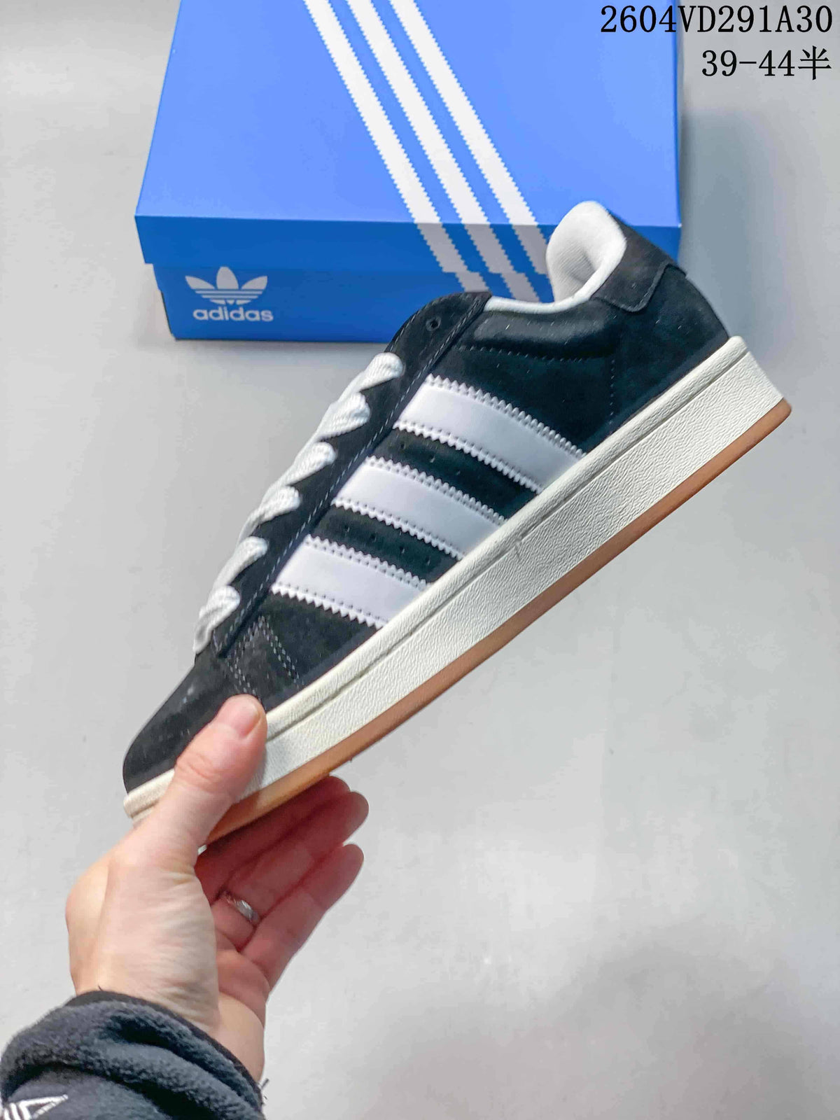 Side profile showing the dark upper, three contrasting stripes, off-white midsole and gum outsole