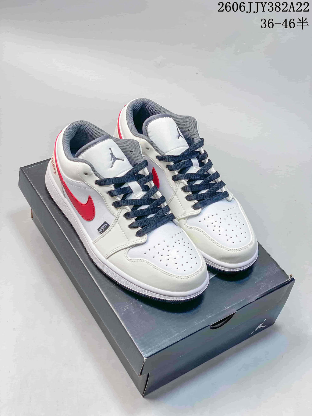 Pair of white low-top Jordan sneakers with red side accents, dark laces, and grey details