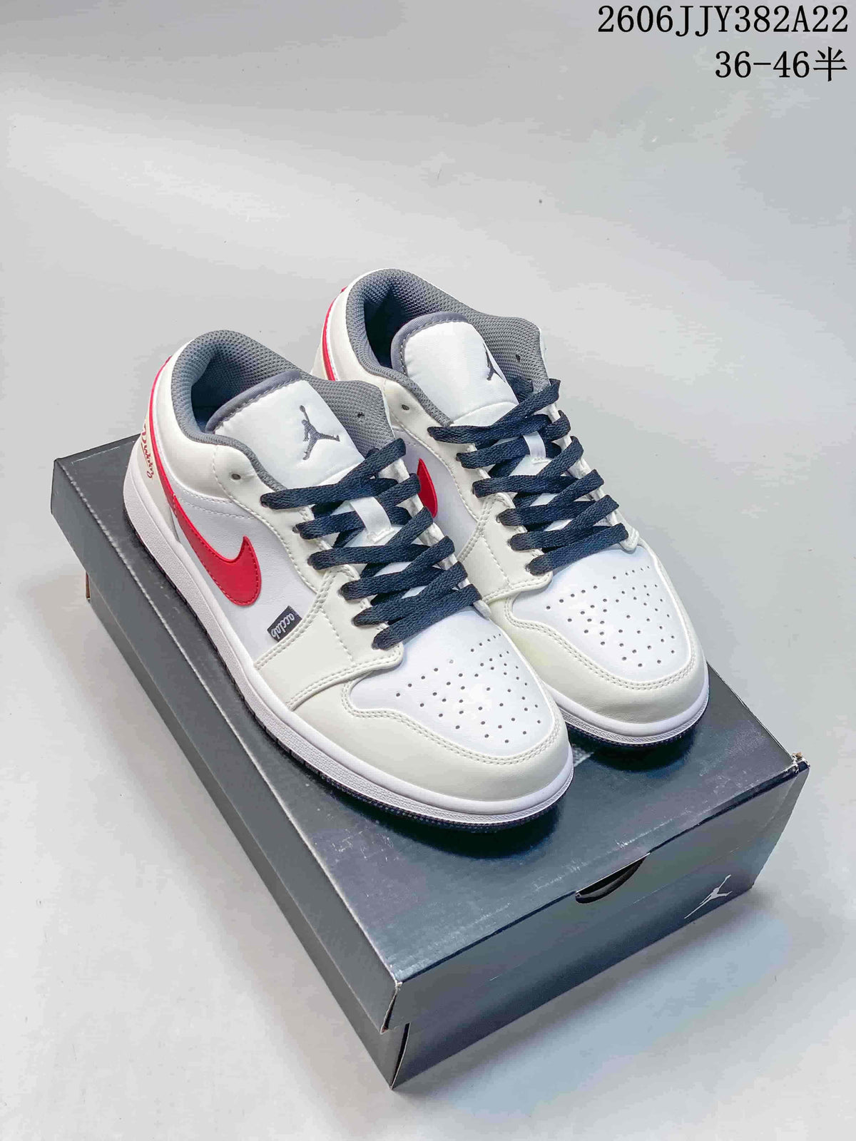 Pair of white low-top Jordan sneakers with red side accents, dark laces, and grey details