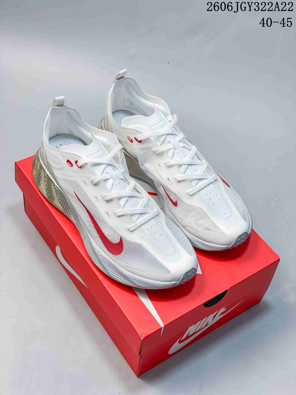 Pair of white Nike Ava X low-top sneakers with red accents, shown on a red shoe box.