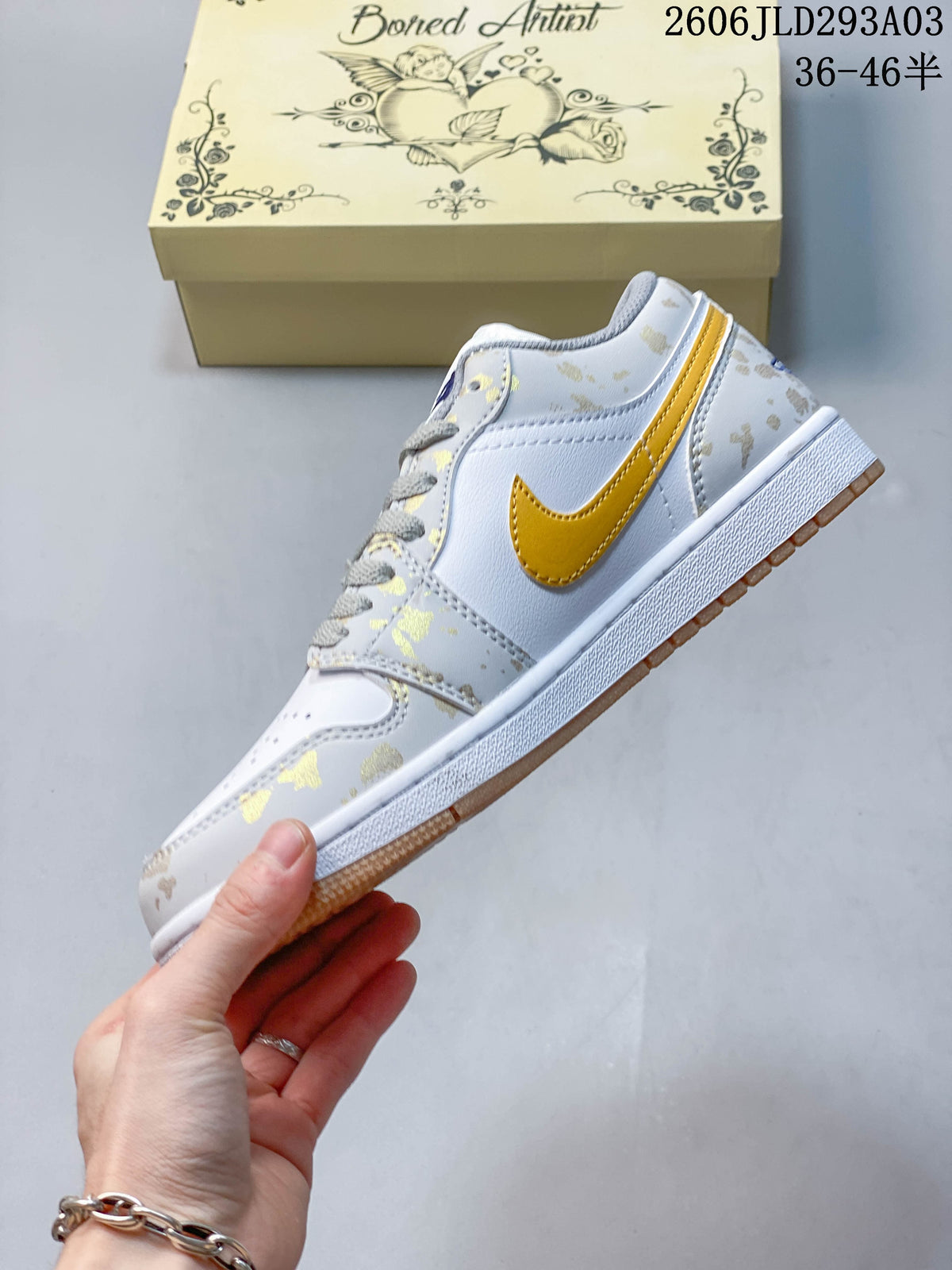 Side view of a white Jordan sneaker with gold-toned accents