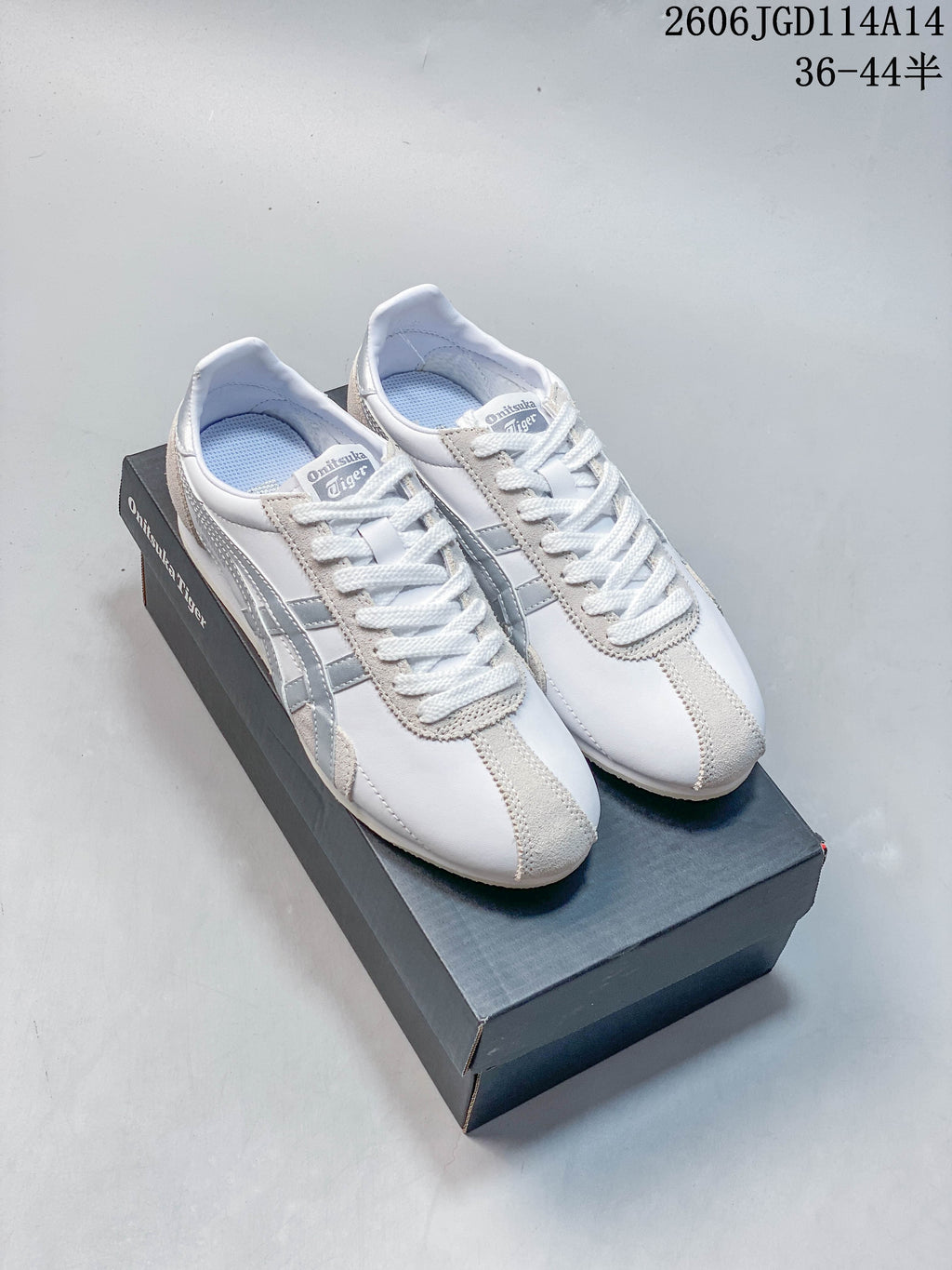 Pair of white and silver Onitsuka Tiger Runspark low-top sneakers displayed on a shoebox
