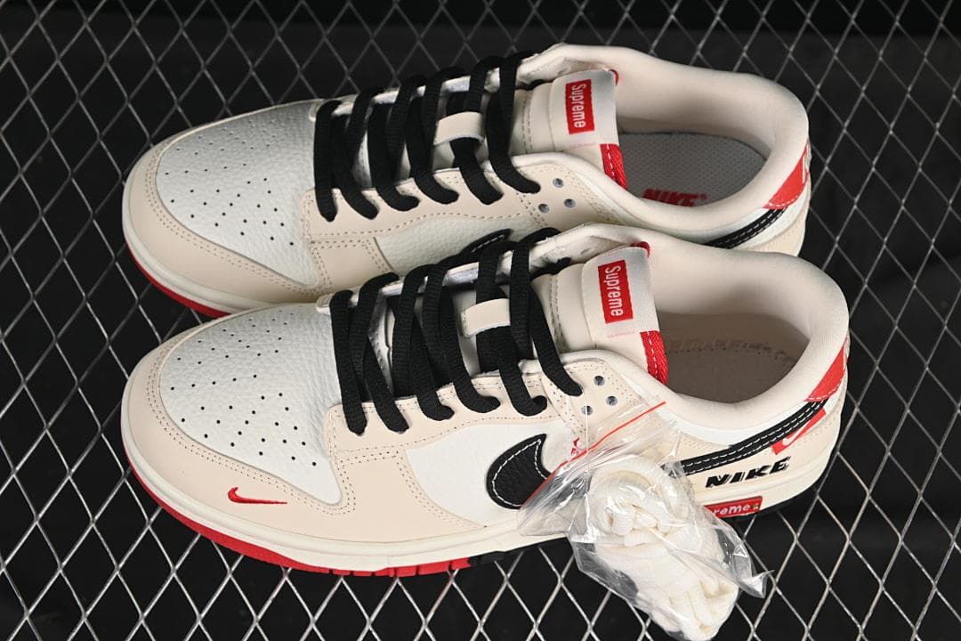 Pair of off-white low-top sneakers shown from above, with perforated toe panels, black laces, red accents, and an extra lace bundle.
