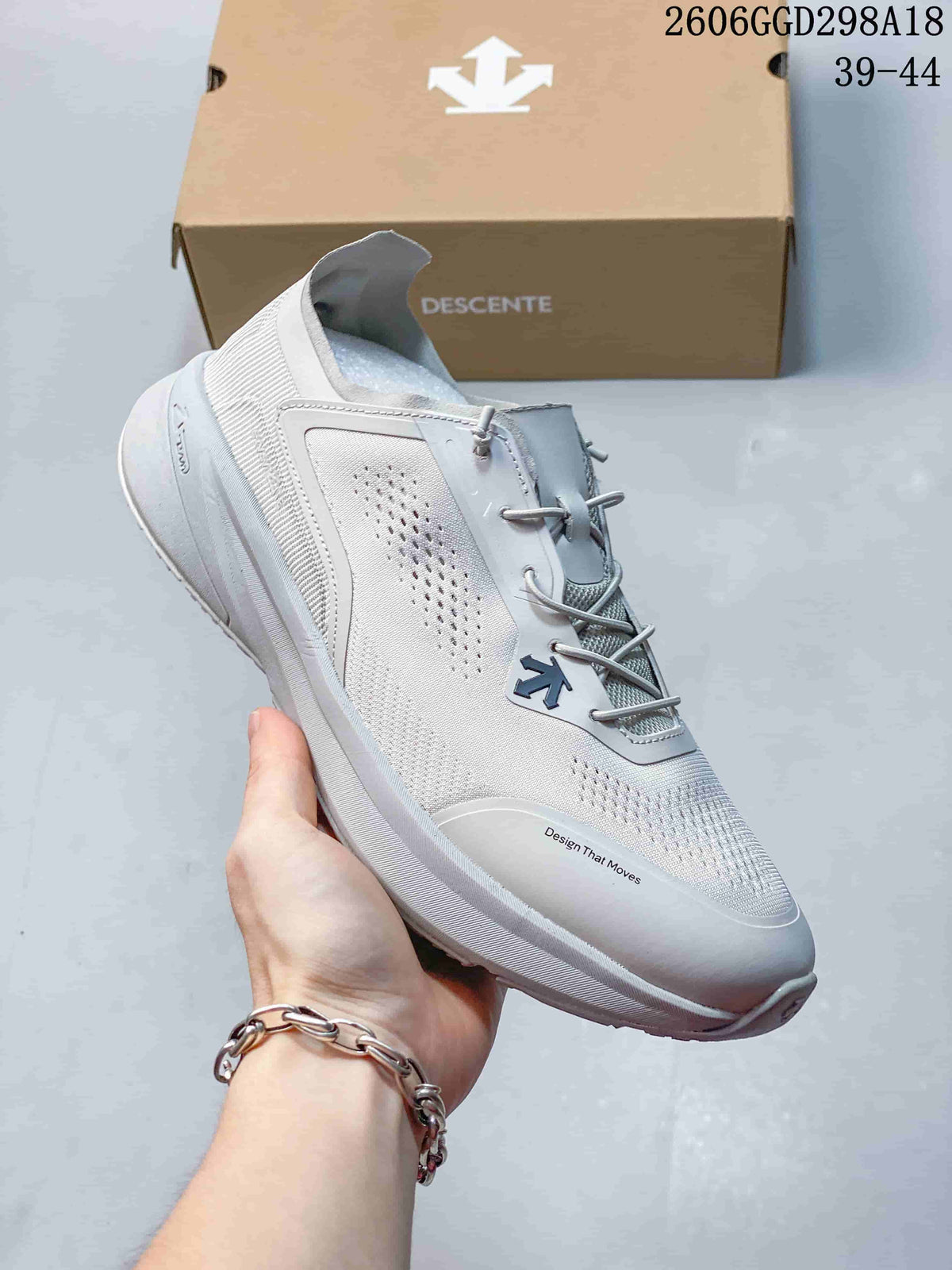 Close-up of a light gray DESCENTE sneaker showing perforated panels and lace-up closure