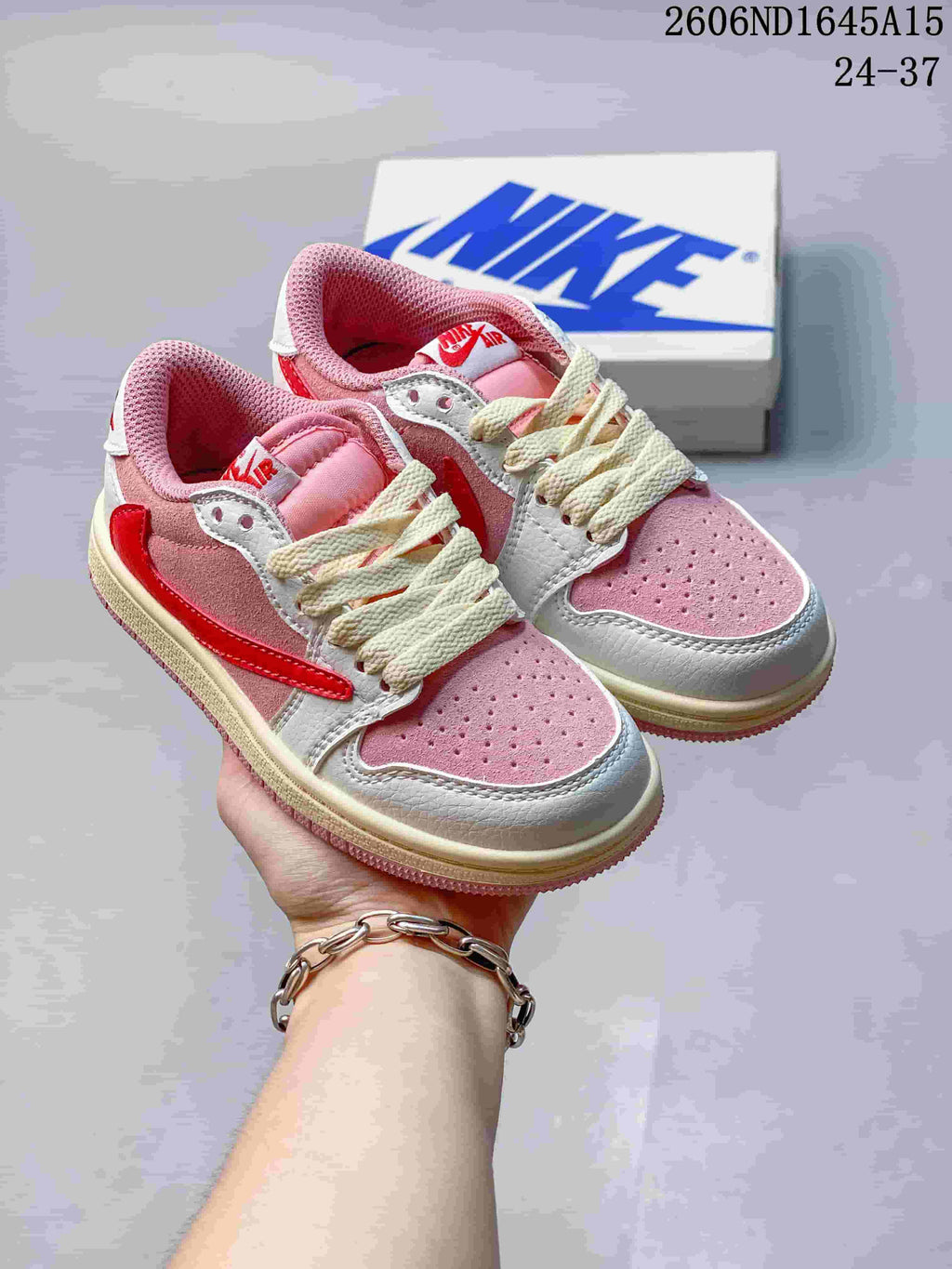 Pair of pink, white, and red kids’ low-top sneakers with cream laces.