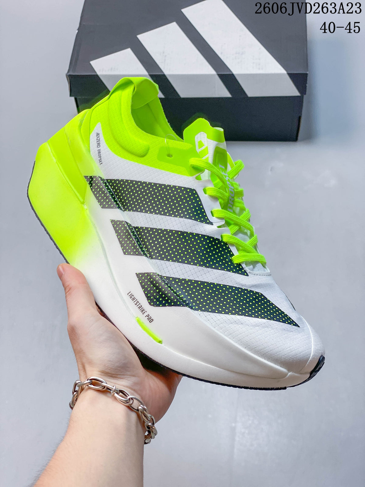 Side view of a white Adizero Dropset Elite shoe with dark stripes and neon yellow-green accents.