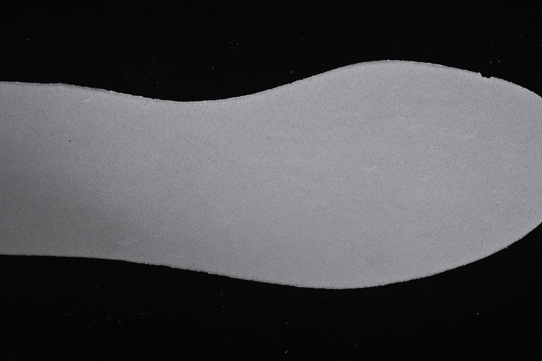 Close-up view of a light-colored shoe insert or sole-shaped component