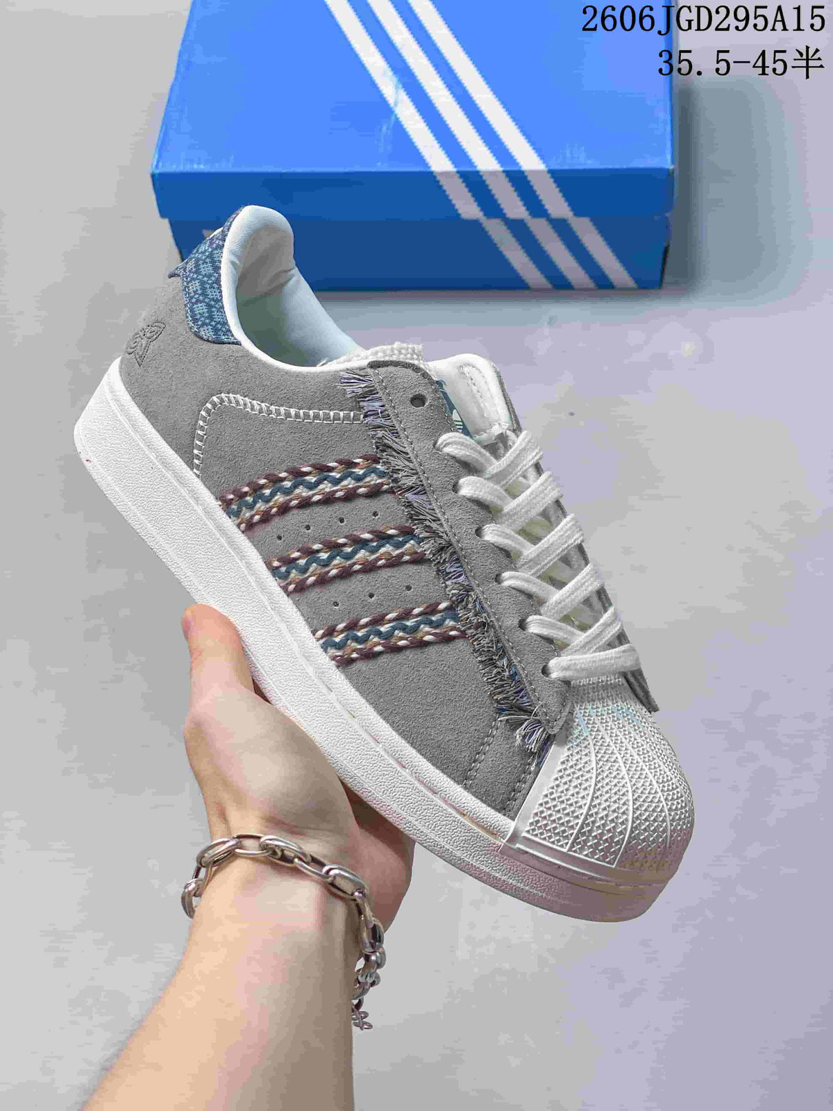 Gray sneaker with multicolor stripe detailing and a shell toe