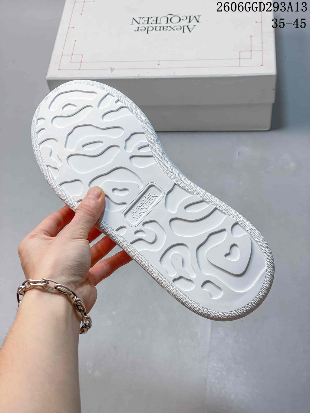 Underside of a white sneaker showing a sculpted tread pattern