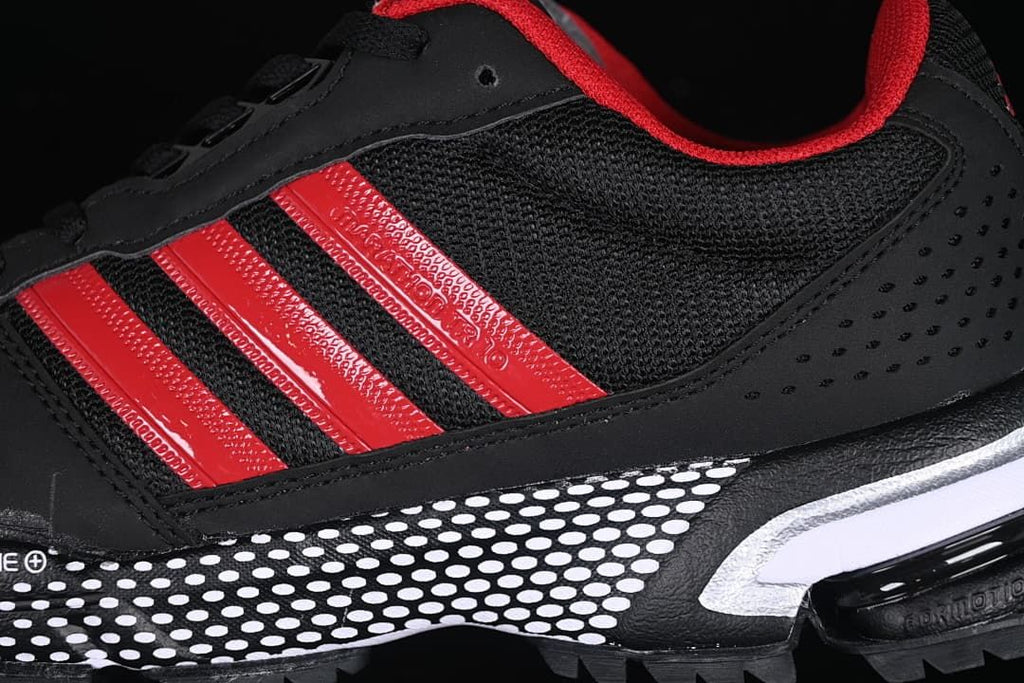 Close-up of red side stripes, black mesh panels, and the dotted midsole.