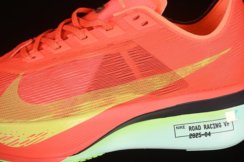 Close-up side view of the coral-orange upper, yellow-green Swoosh and midsole label.