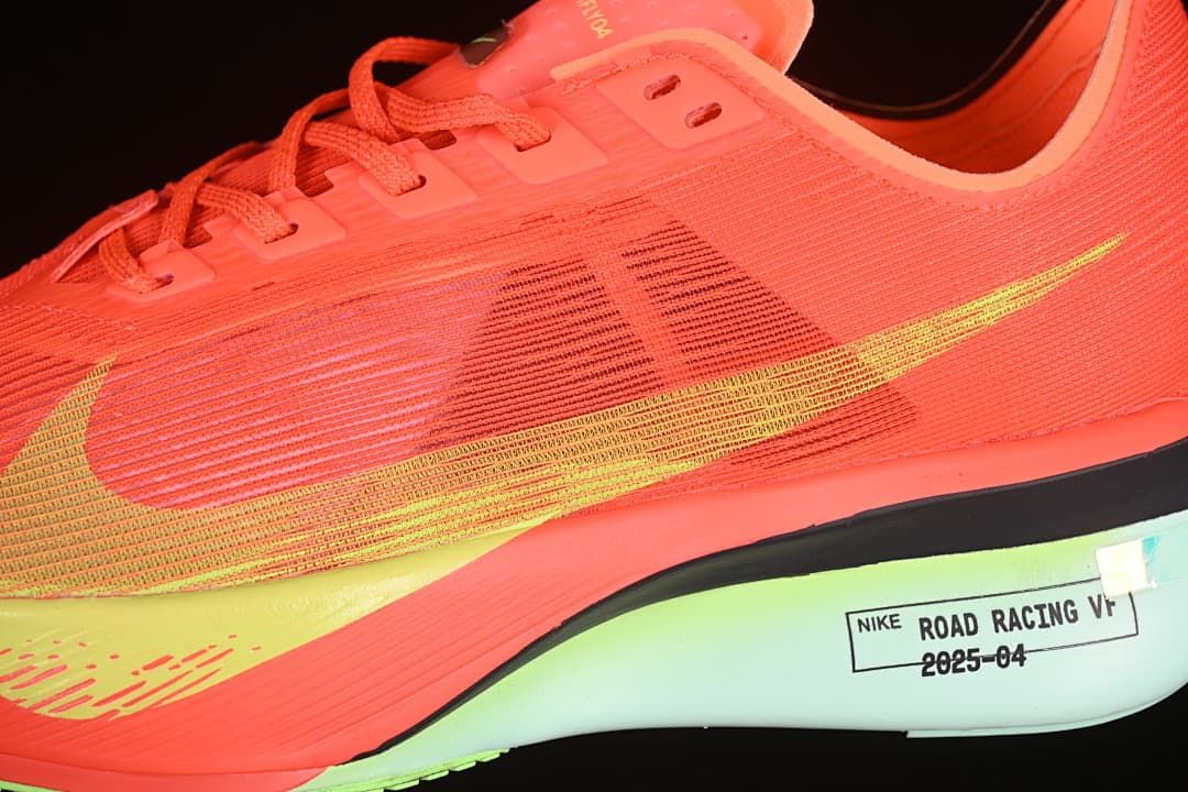 Close-up side view of the coral-orange upper, yellow-green Swoosh and midsole label.