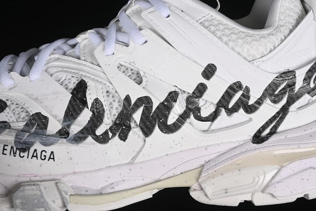 Close-up of black graphic lettering across the white sneaker side