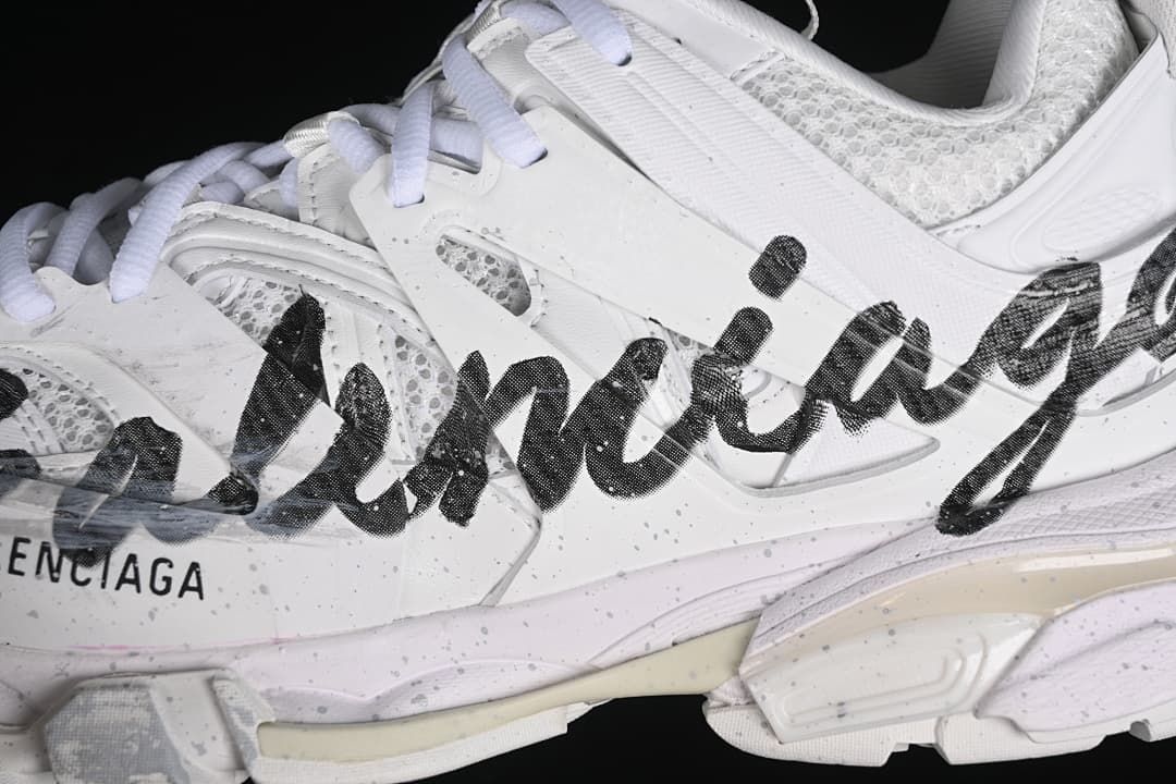 Close-up of black graphic lettering across the white sneaker side