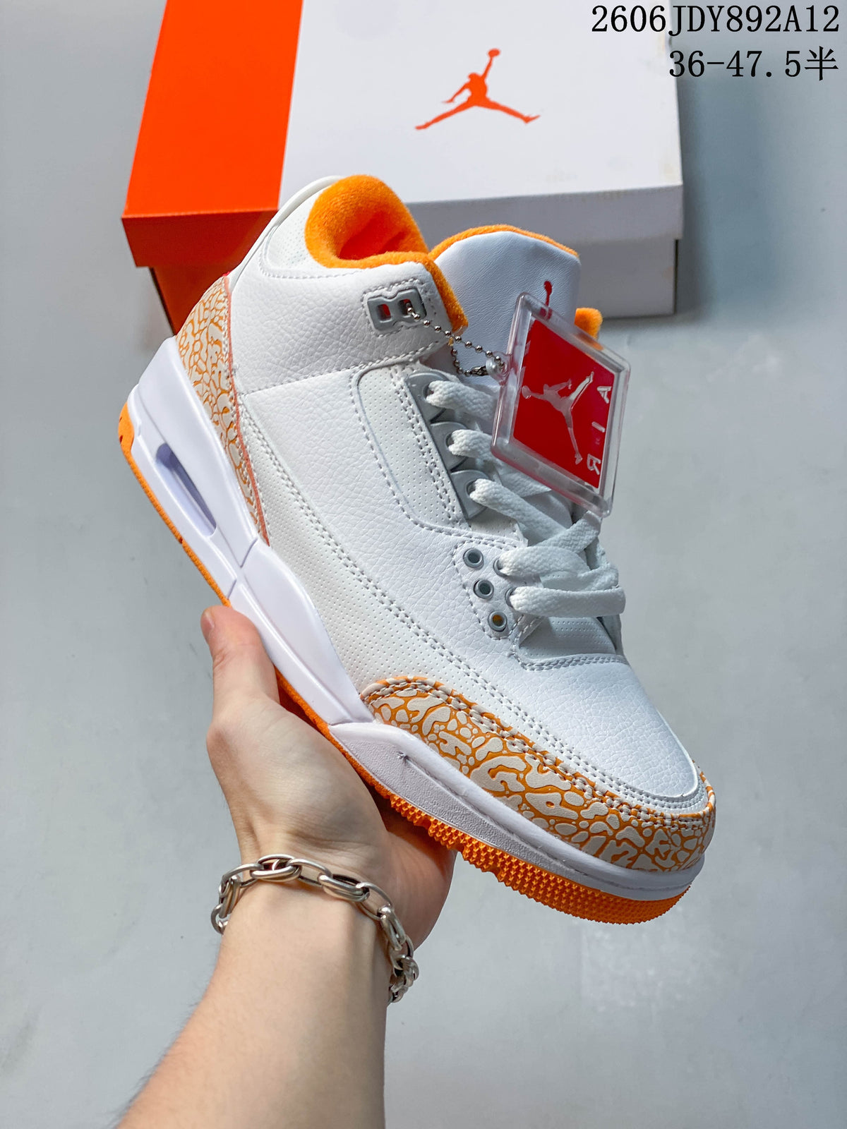 Angled side view of a white and orange Air Jordan 3 Retro sneaker.